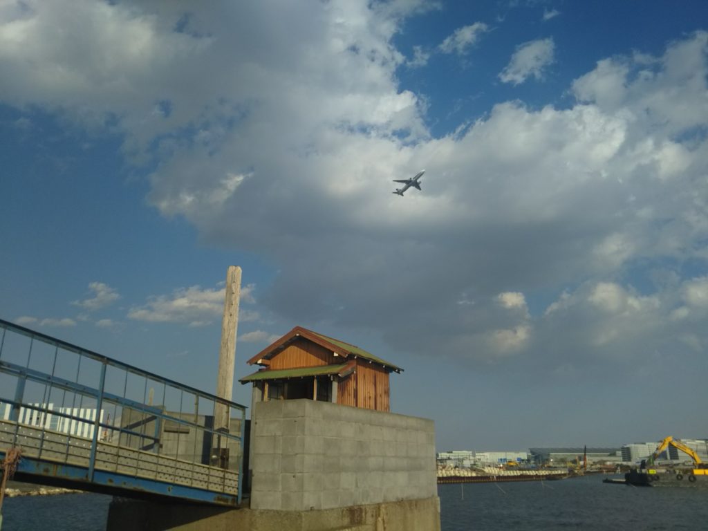 大田区羽田の五十間鼻の無縁仏堂の上を新飛行ルートの飛行機が飛びます。